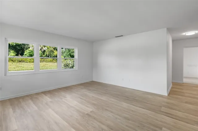 a view of an empty room with wooden floor and windows