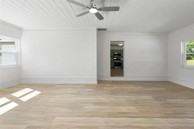 a view of an empty room with window and chandelier fan