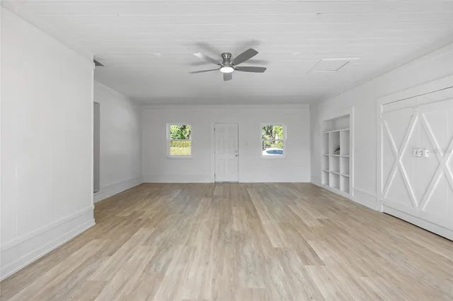 an empty room with windows and ceiling fan view