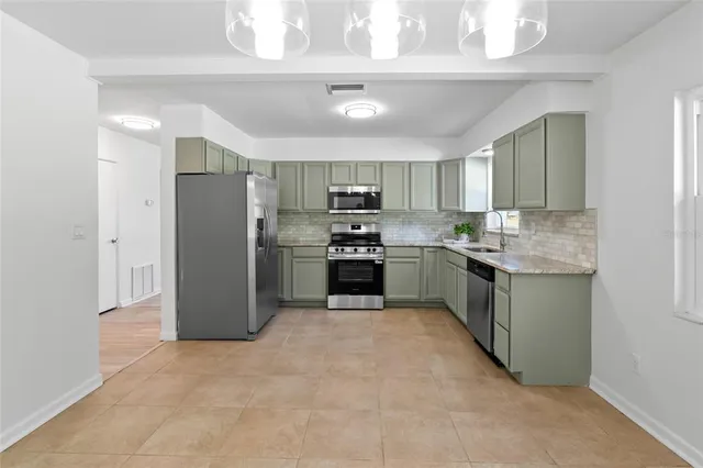 a kitchen with stainless steel appliances granite countertop a refrigerator a stove a sink and a microwave