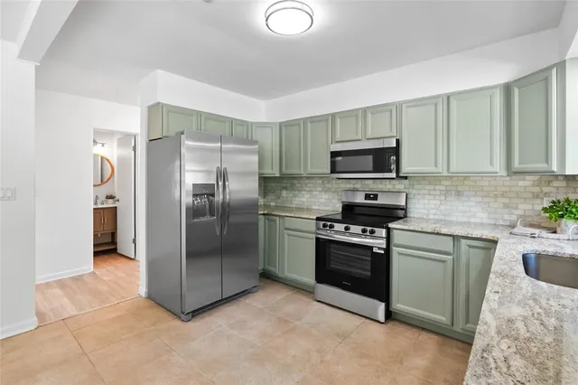 a kitchen with granite countertop a refrigerator and a stove top oven