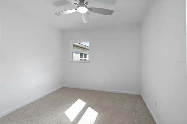 an empty room with a chandelier fan and windows