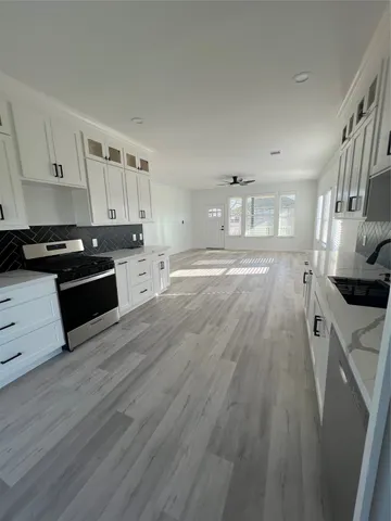 a large kitchen with cabinets wooden floor and stainless steel appliances