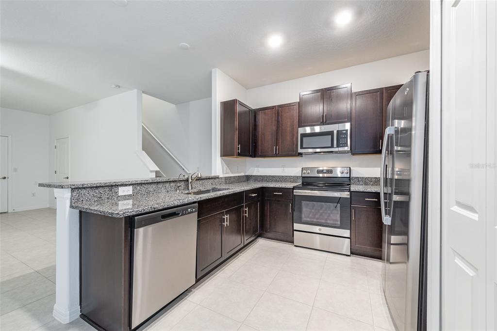 14348 Editors Note Street Ruskin, FL 33573 - Photo 7 of 24 a kitchen with stainless steel appliances granite countertop a stove and a sink