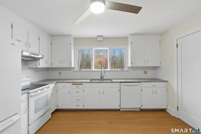 a kitchen with granite countertop a sink cabinets and stainless steel appliances