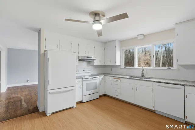 a kitchen with granite countertop white cabinets and white appliances