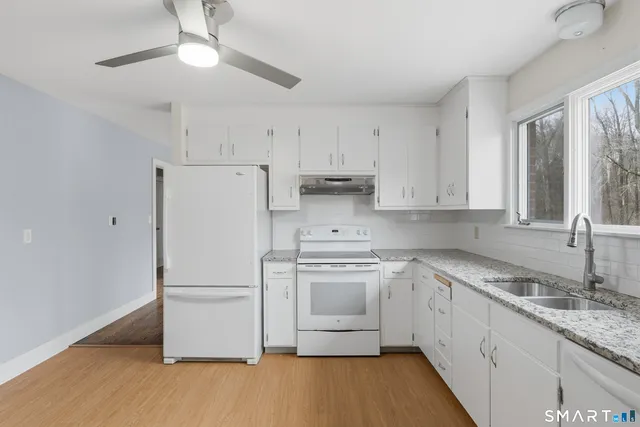 a kitchen with granite countertop white cabinets and white appliances