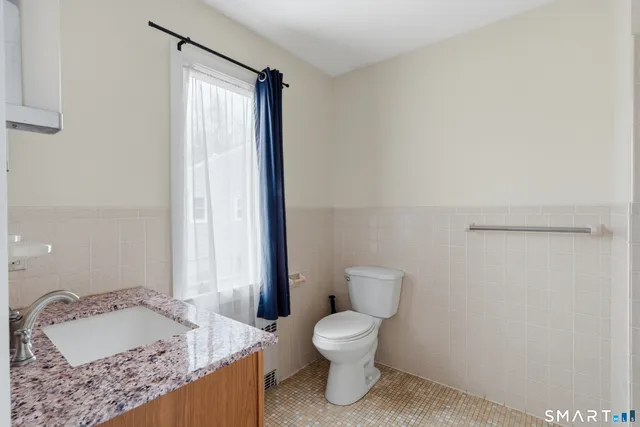 a bathroom with a granite countertop sink and a toilet