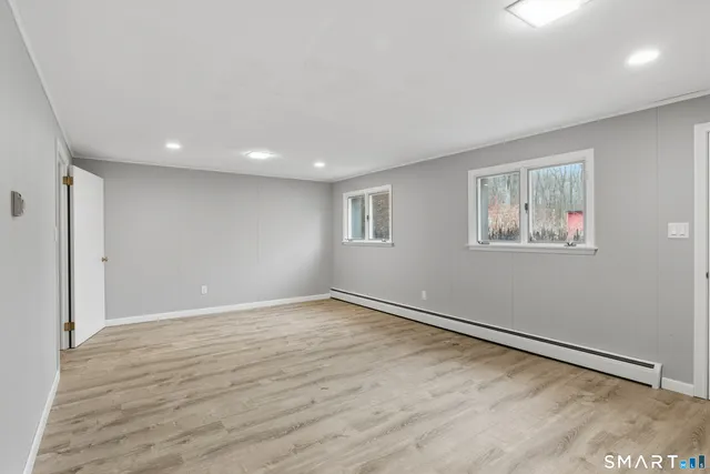 a view of an empty room with wooden floor and a window