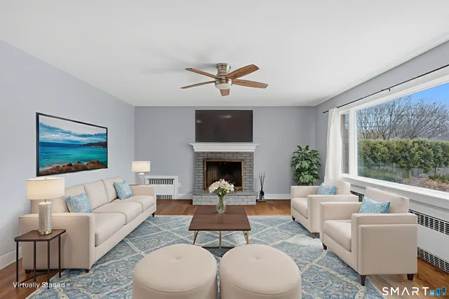 a living room with furniture a fireplace and a large window