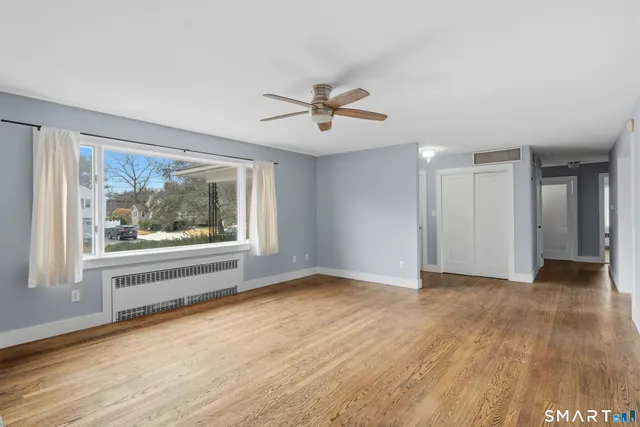 a view of empty room with wooden floor and fan