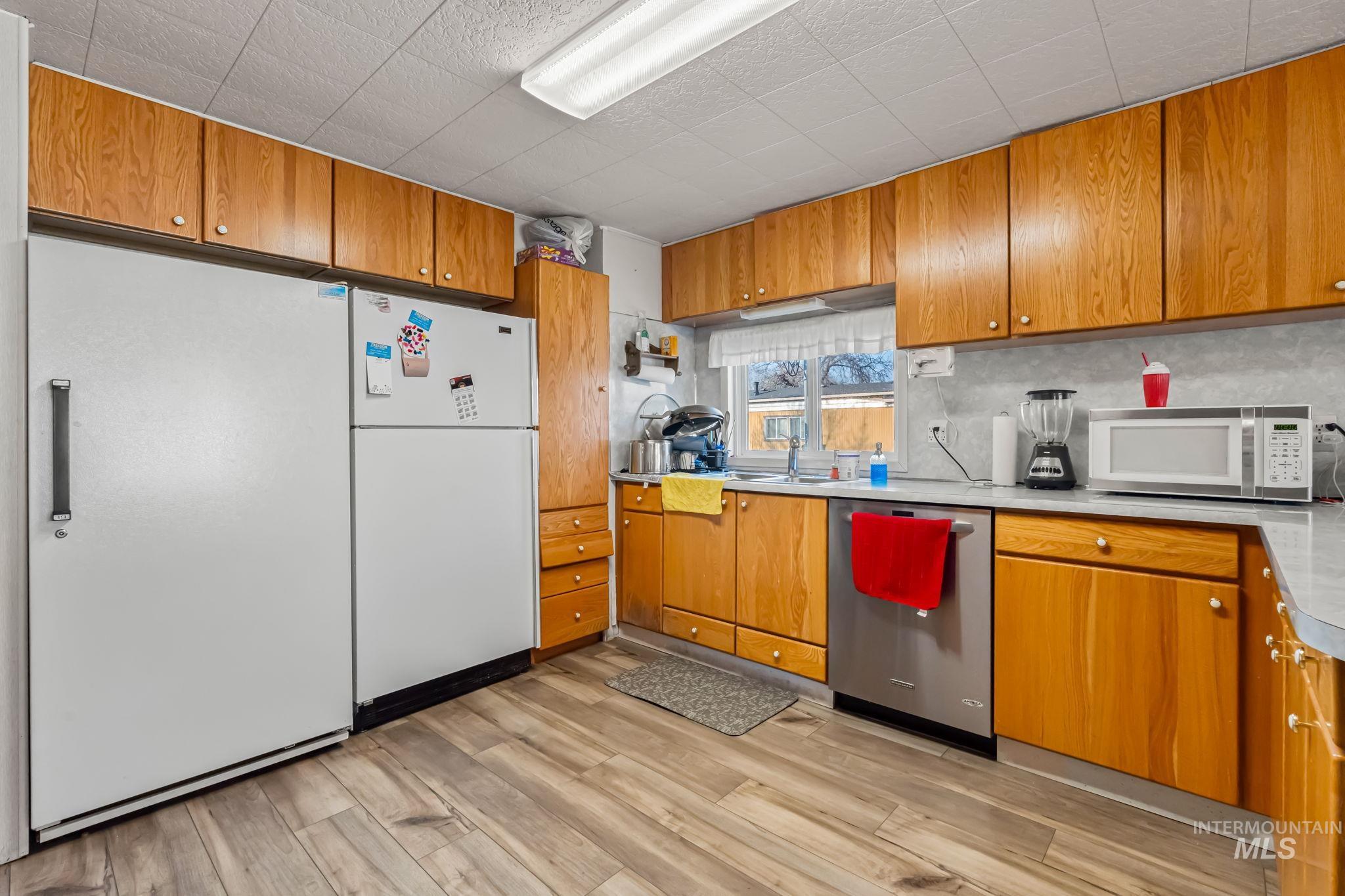 11234 George Street Nampa, ID 83651 - Photo 14 of 25 Kitchen featuring freestanding refrigerator, light countertops, stainless steel dishwasher, and light wood-style flooring