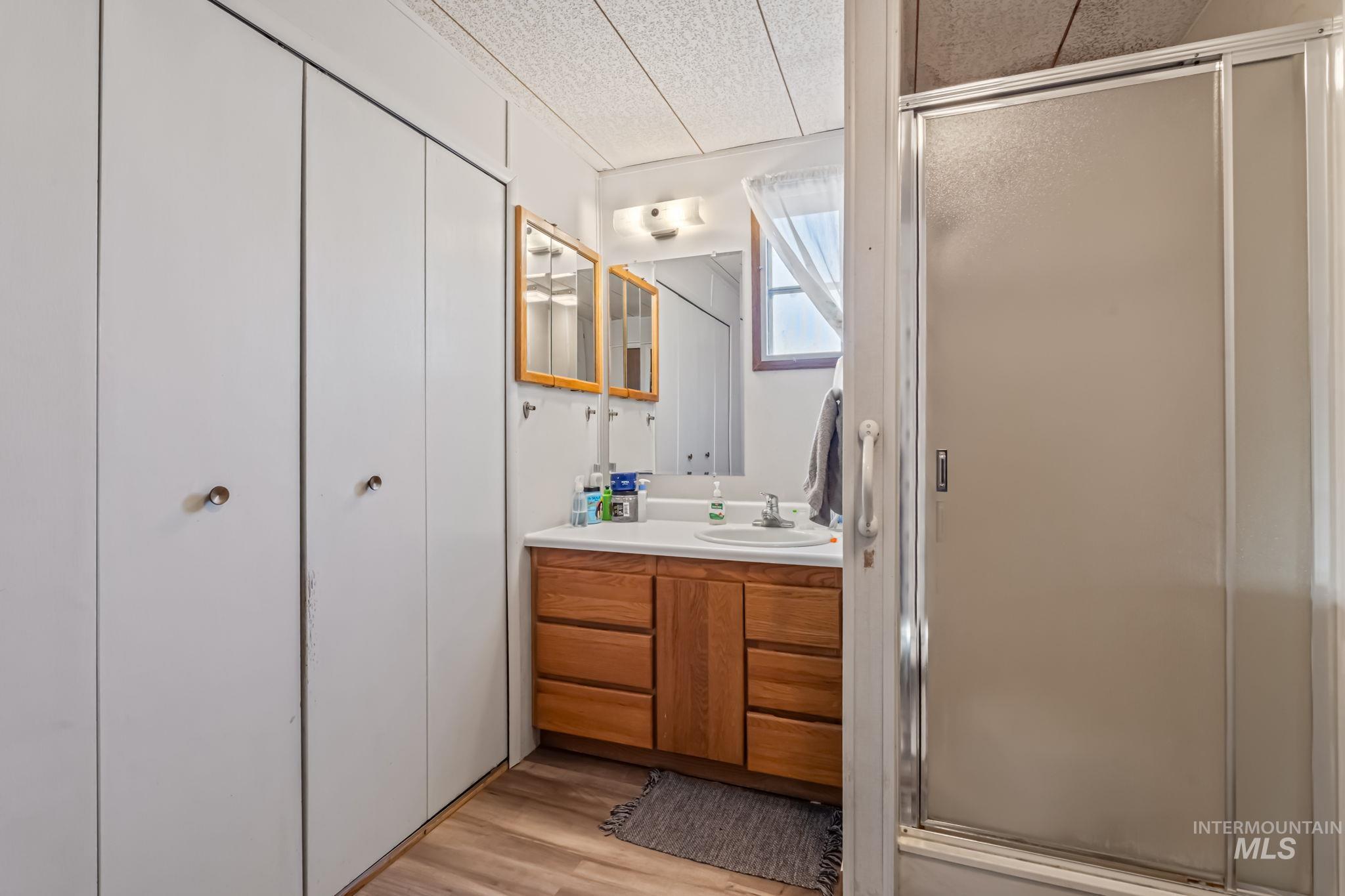 11234 George Street Nampa, ID 83651 - Photo 19 of 25 Bathroom featuring light wood-style floors, vanity, a shower stall, and a textured ceiling