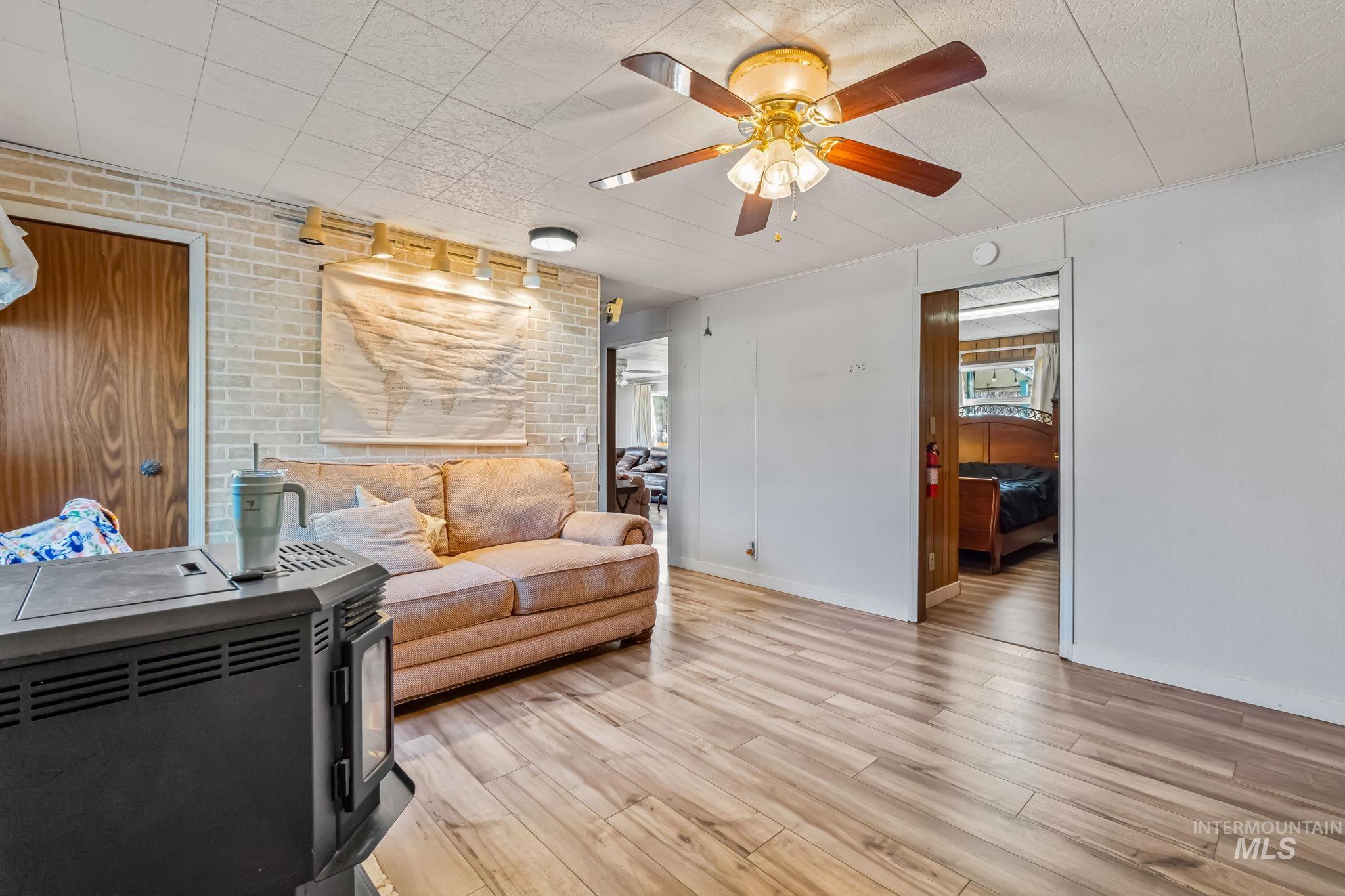 11234 George Street Nampa, ID 83651 - Photo 8 of 25 Living room with wood finished floors, a wood stove, a ceiling fan, and brick wall