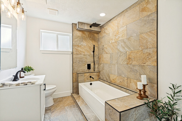 62 South Clark Lane Elk Ridge, UT 84651 - Photo 21 of 30 Bathroom featuring a tiled accent wall, white soaking tub with matte black fixtures, a rain shower head, and a white vanity with a rectangular undermount sink