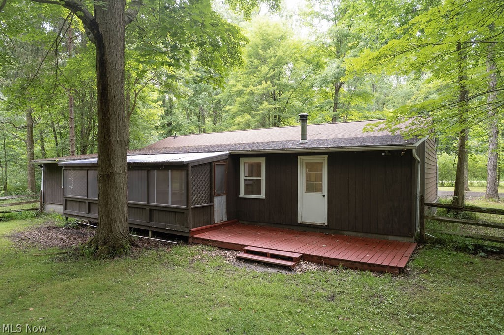 18620 Shaw Road Chagrin Falls, OH 44023 - Photo 44 of 44 Brown siding exterior featuring a white entry door, a red-stained wooden deck, and a screened-in porch