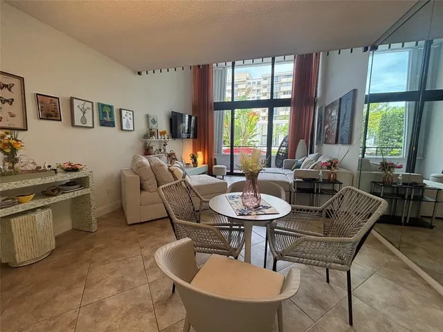 a living room with furniture a large window and dining table