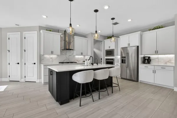 a kitchen with stainless steel appliances granite countertop a refrigerator a sink dishwasher a stove and white cabinets with wooden floor