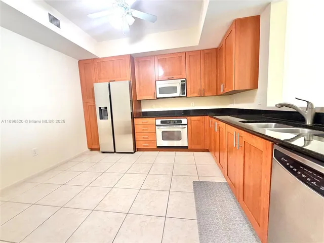 a kitchen with stainless steel appliances a sink a stove a refrigerator cabinets and a dining table