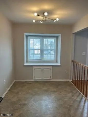 an empty room with chandelier fan and windows