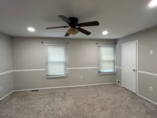 an empty room with windows and fan