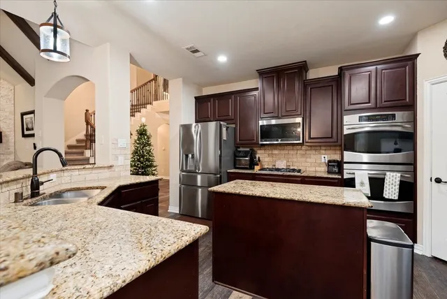 a kitchen with stainless steel appliances granite countertop a refrigerator a stove top oven a sink and dishwasher