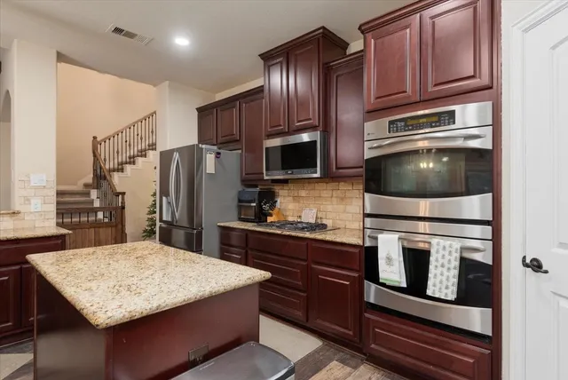 a kitchen with stainless steel appliances wooden cabinets and center island