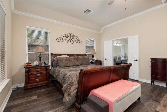 a bedroom with a bed and dresser with wooden floor