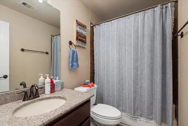 a bathroom with a granite countertop sink vanity mirror and toilet