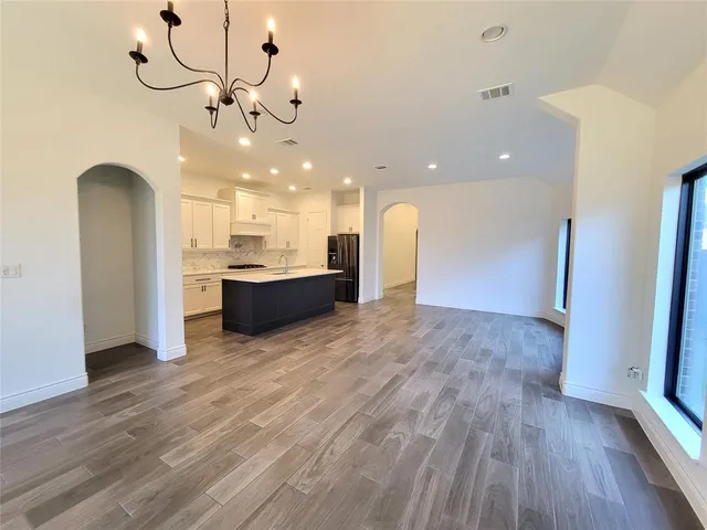 an empty room with wooden floor and kitchen