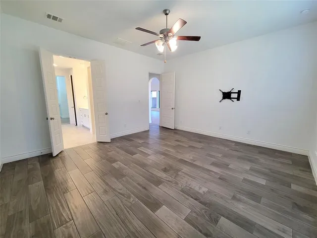 an empty room with wooden floor and a ceiling fan