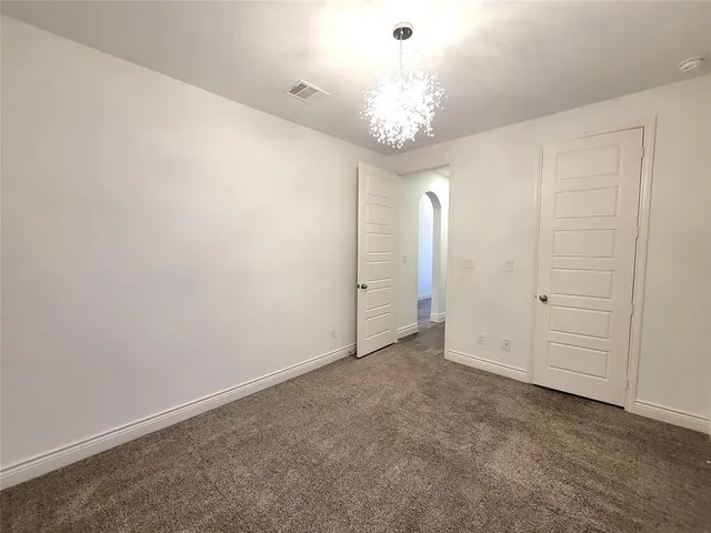 an empty room with a chandelier fan and entryway