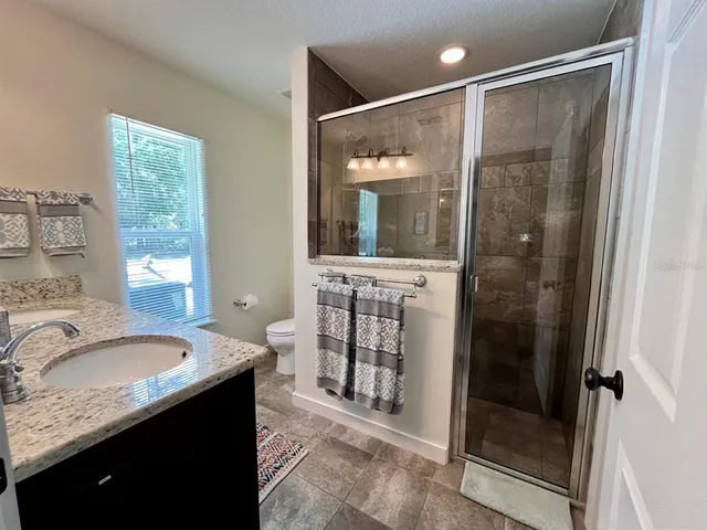a bathroom with a granite countertop sink mirror and shower