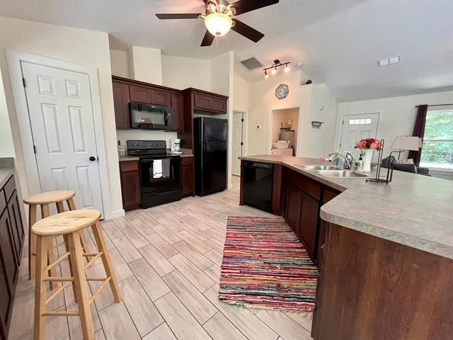 a large kitchen with stainless steel appliances kitchen island granite countertop a refrigerator and a sink