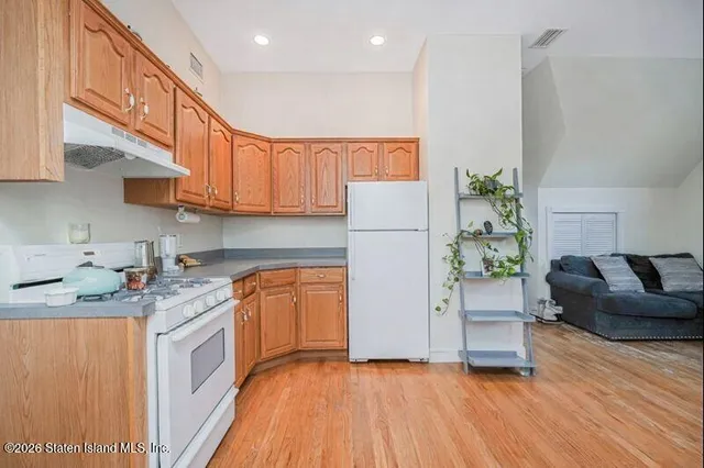 a kitchen with a refrigerator a stove top oven a counter space and wooden floor