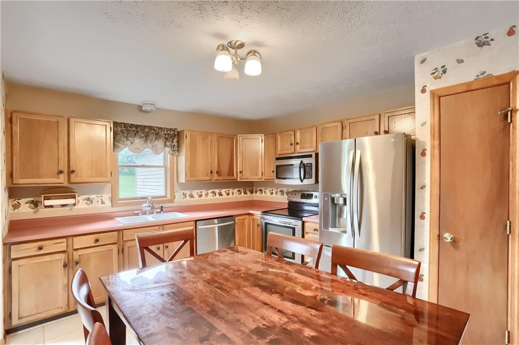 135 Staff Road Slippery Rock, PA 16057 - Photo 11 of 25 a kitchen with stainless steel appliances granite countertop a refrigerator a stove a sink a dining table and chairs with wooden floor
