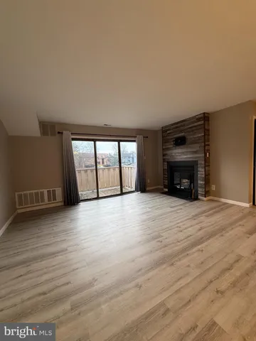a view of empty room with wooden floor and fireplace