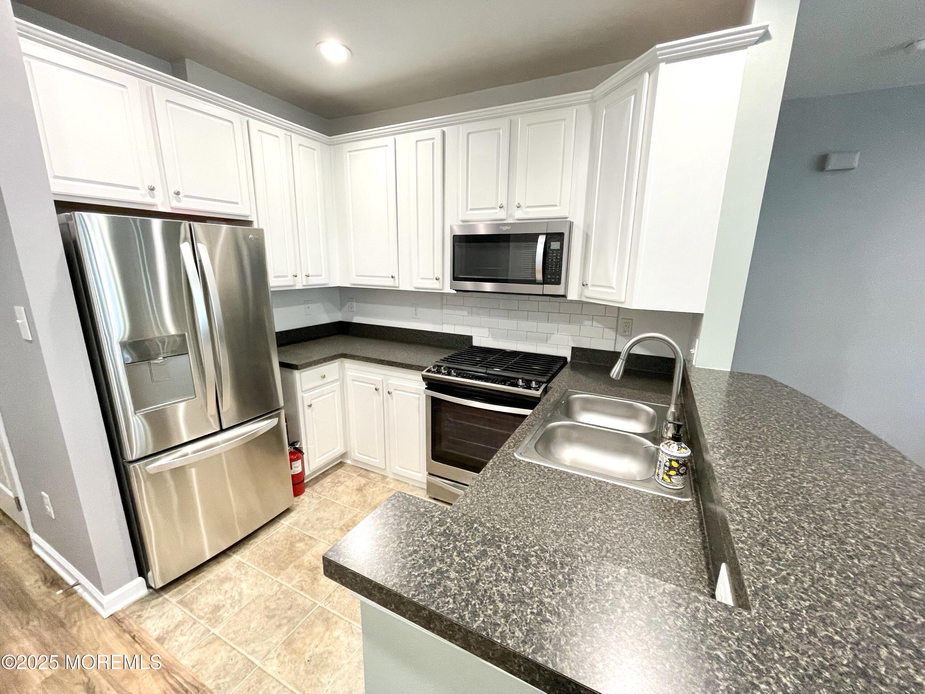 46 Michael Drive Tinton Falls, NJ 07712 - Photo 6 of 16 a kitchen with granite countertop a refrigerator a sink a stove a microwave and cabinets