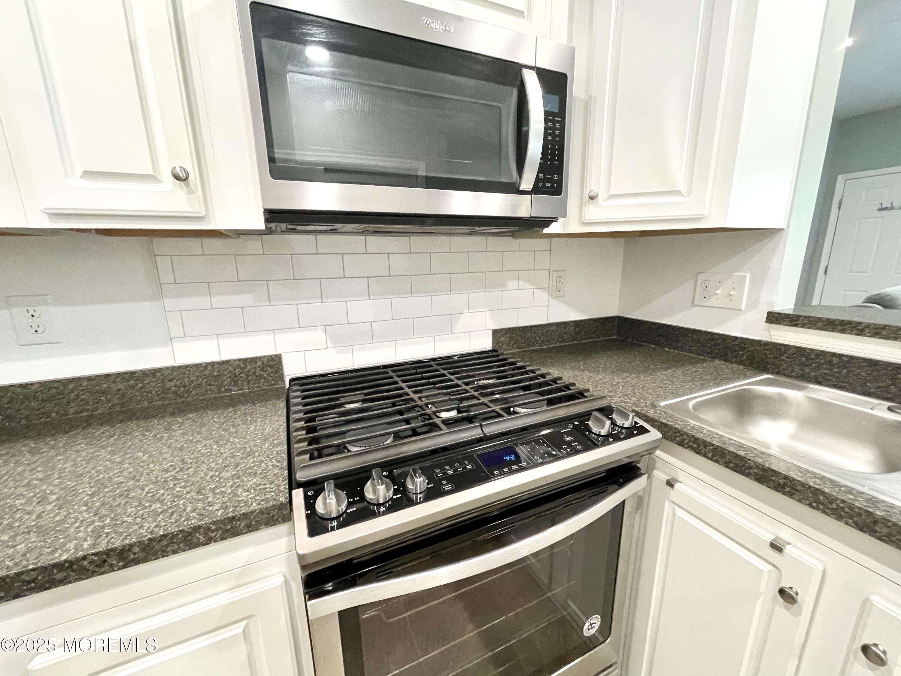 46 Michael Drive Tinton Falls, NJ 07712 - Photo 7 of 16 a kitchen with granite countertop white cabinets and appliances