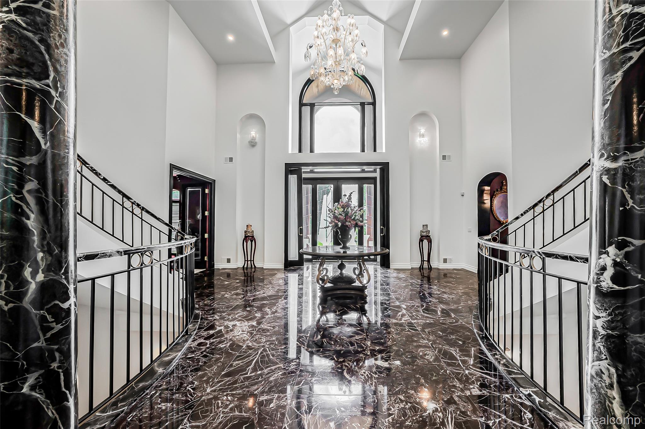 2785 Cranbrook Ridge Court Rochester, MI 48306 - Photo 58 of 99 Two-story foyer featuring marble flooring, dual curved staircases with wrought iron railings, a vaulted ceiling, and an arched transom window