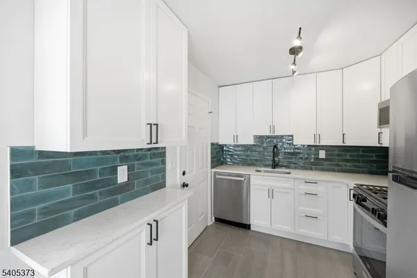a kitchen with granite countertop white cabinets stainless steel appliances and sink