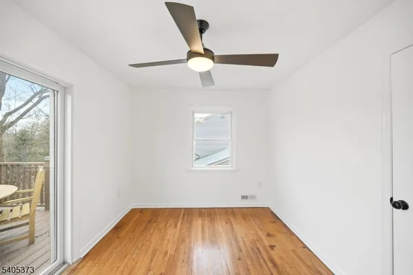 an empty room with wooden floor cabinet and windows