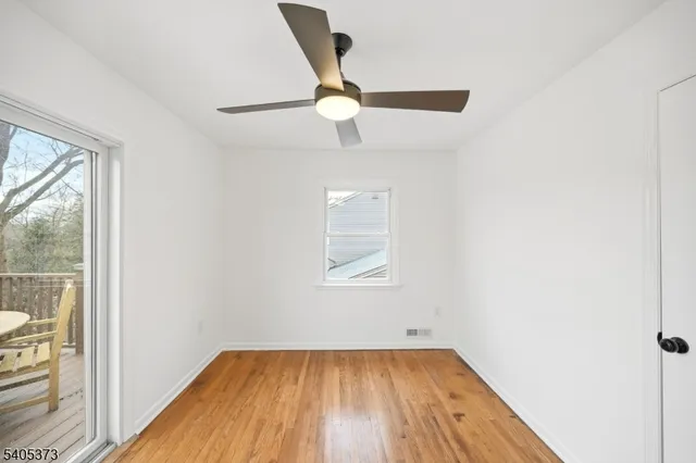 an empty room with wooden floor cabinet and windows