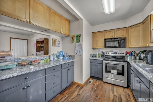 a kitchen with stainless steel appliances granite countertop a stove a sink dishwasher and a microwave oven with wooden floor