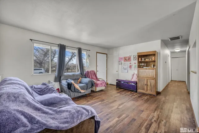 a spacious bedroom with a bed and wooden floor