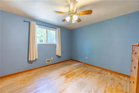 a view of an empty room with window and wooden floor