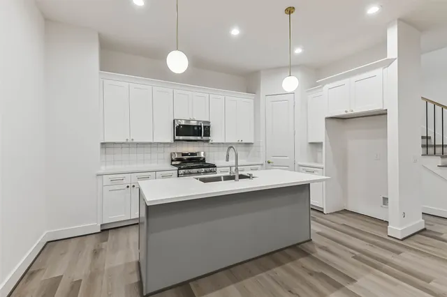 a kitchen with stainless steel appliances granite countertop white cabinets and a stove top oven