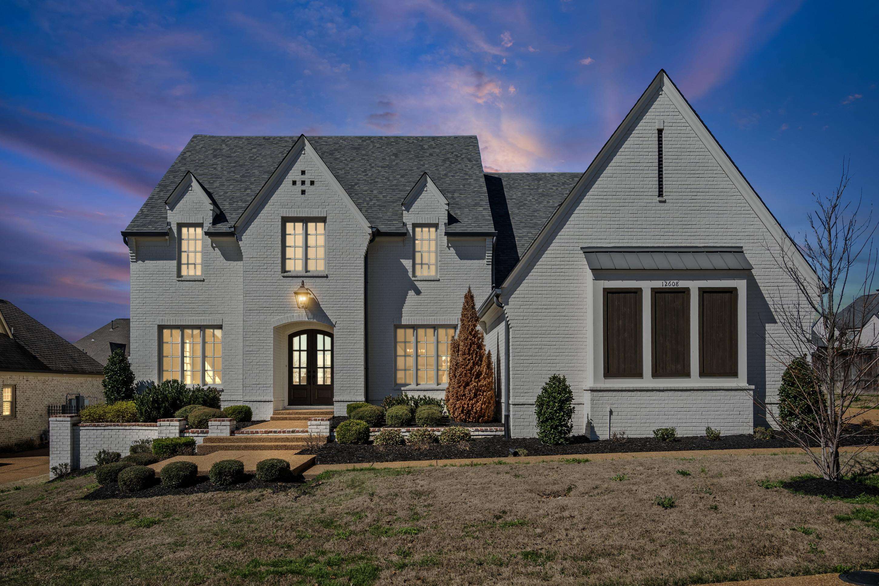 View of front of home with brick siding, french doors, and a yard