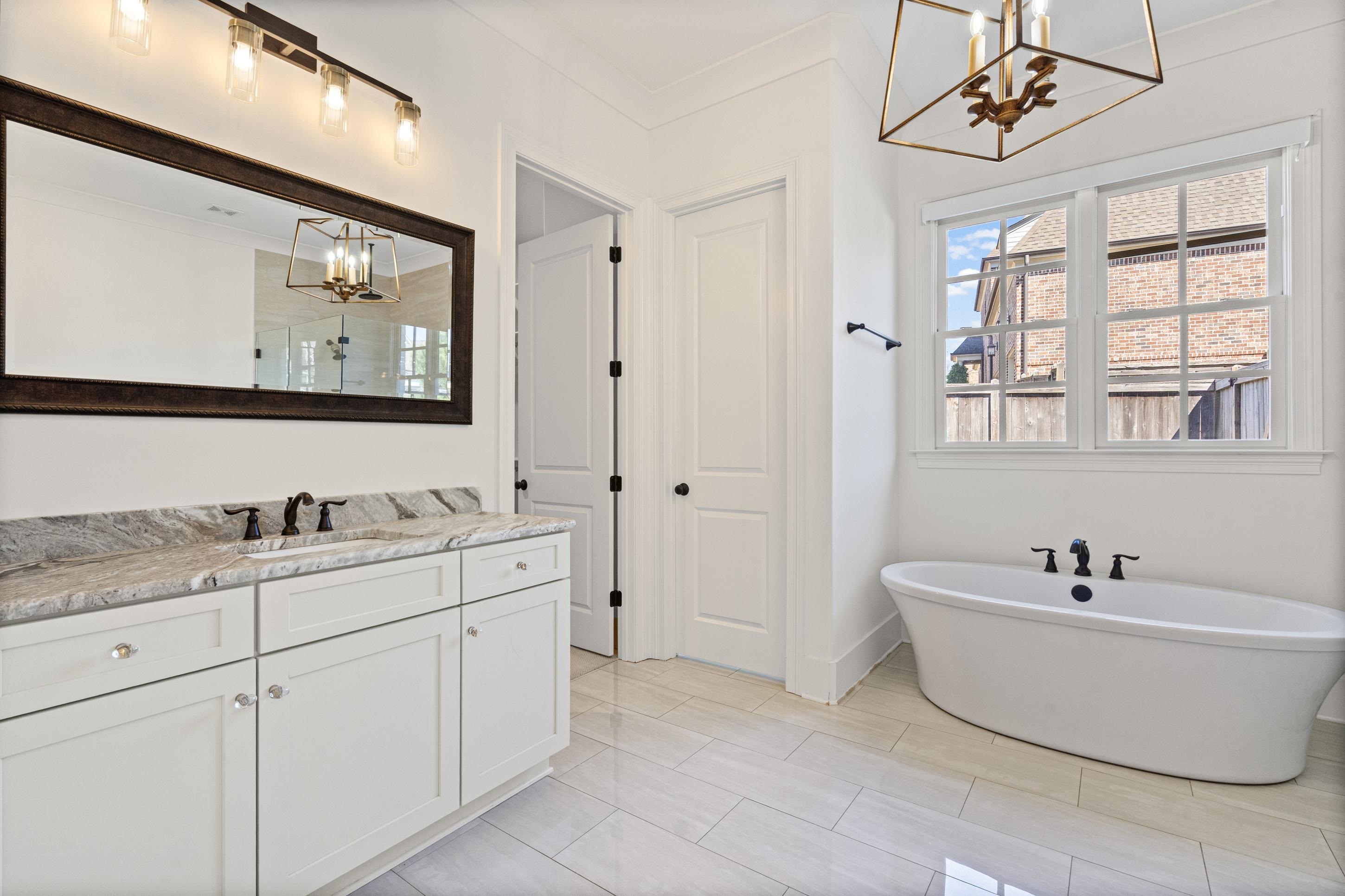 12608 Bravo Road Collierville, TN 38017 - Photo 14 of 40 Full bathroom featuring a chandelier, vanity, a freestanding tub, and crown molding