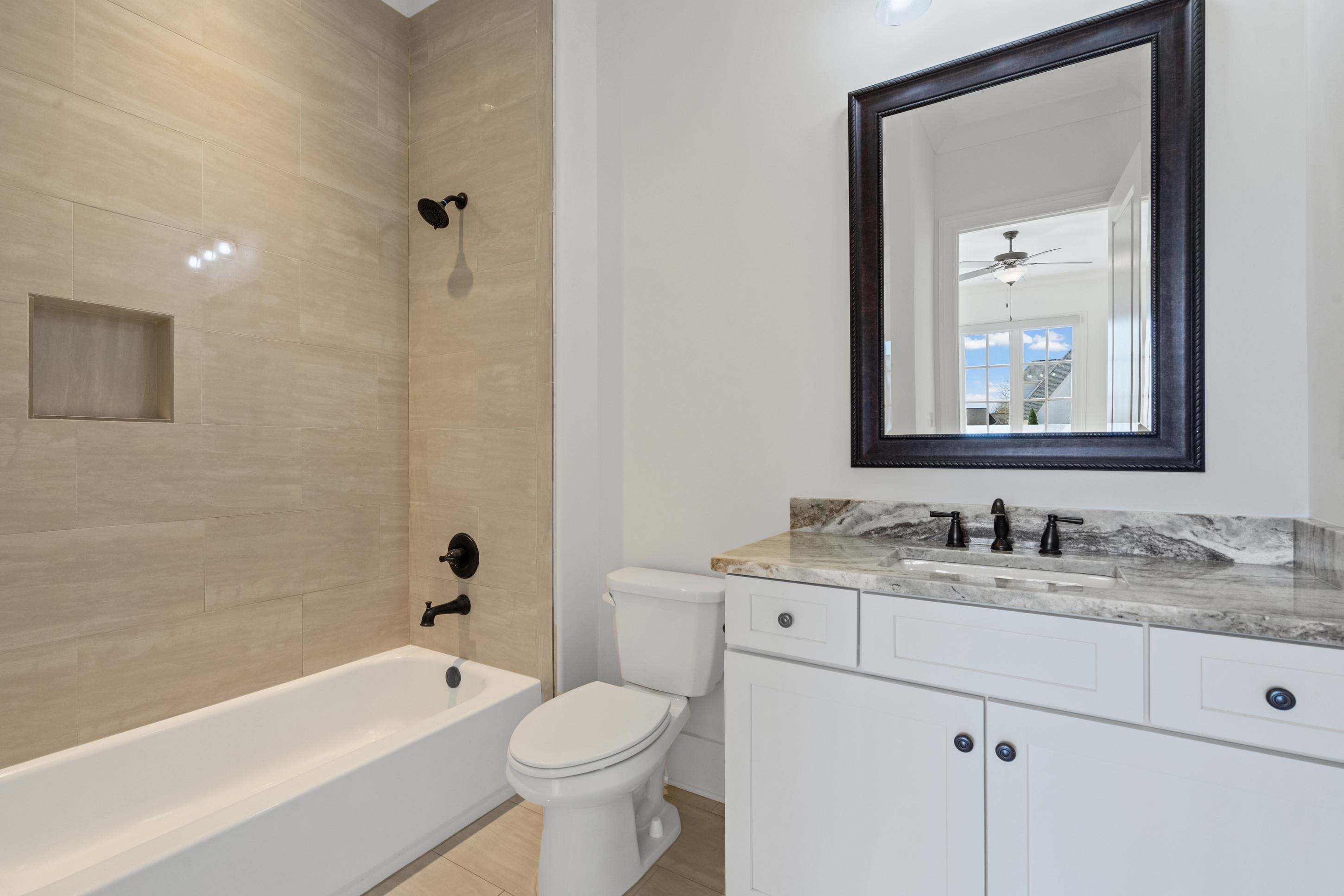 12608 Bravo Road Collierville, TN 38017 - Photo 18 of 40 a bathroom with a toilet a sink a mirror a bathtub and vanity